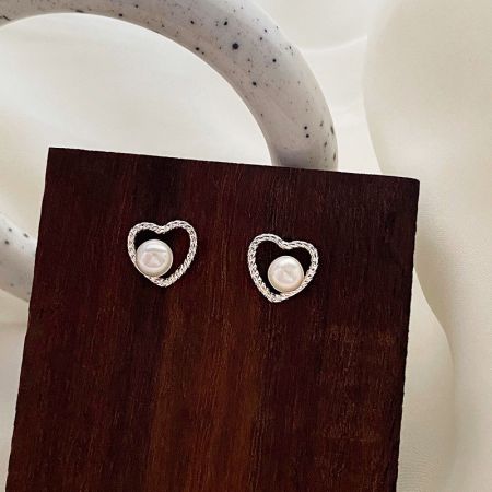 Vista dettagliata degli orecchini a forma di cuore con perle, che mette in evidenza l'artigianato in argento e la perla centrale.