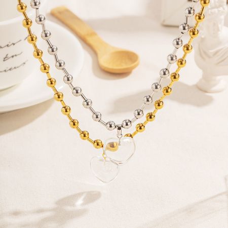 Roestvrijstalen Chunky Ball Chain Hart Hanger Ketting - Een paar roestvrijstalen chunky ball chain kettingen, één in goud en één in zilver, elk met een transparante kwarts glazen hart hanger.