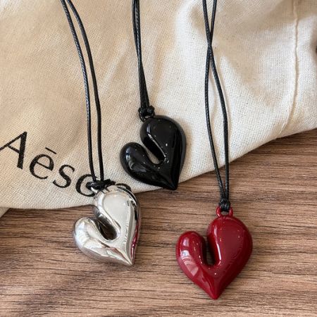 A trio of modern heart-shaped pendants in silver, black, and red, showcasing the variety of styles available.