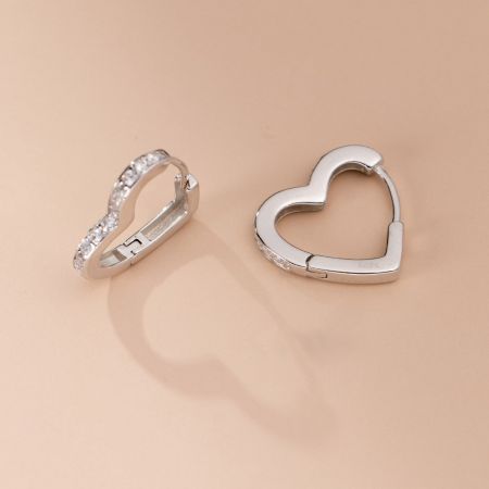 Scatto macro che rivela il timbro 'S925' sugli orecchini a forma di cuore, confermando la loro qualità in argento sterling.