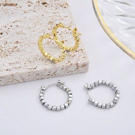 A stylish arrangement of three pairs of hoop earrings in gold and silver on a decorative plate.