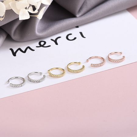 Il set completo di orecchini a cuffia non forati in tre colori esposto su una scheda 'merci'.