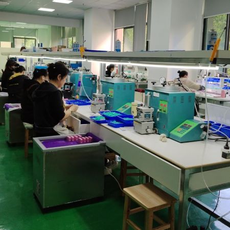 Prácticas de fabricación responsables con el medio ambiente de JR Fashion Accessories - Un taller limpio y organizado en JR Fashion Accessories, mostrando su proceso de fabricación responsable con el medio ambiente con técnicos en sus estaciones de trabajo.