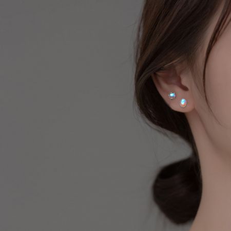 Primo piano di un orecchino a perno in argento sterling con una affascinante pietra di luna iridescente.