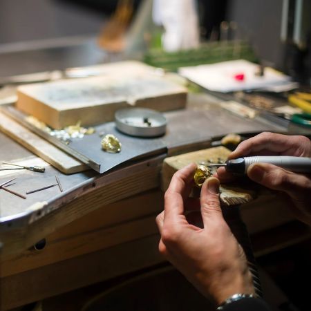 Un abile orafo che crea meticolosamente un pezzo di gioielleria personalizzata, evidenziando l'expertise produttiva di JR Fashion Accessories.