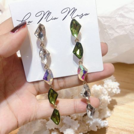 Vue complète des boucles d'oreilles pendantes remarquables sur une carte d'affichage de marque, mettant en avant leur longueur et leur design.
