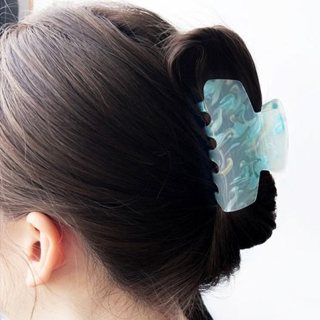 A model wearing a large light blue hair clip in her bun.