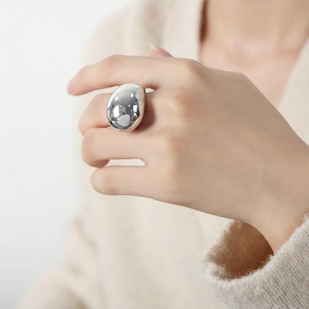 A person wearing the large, oval-shaped silver ring from the set.