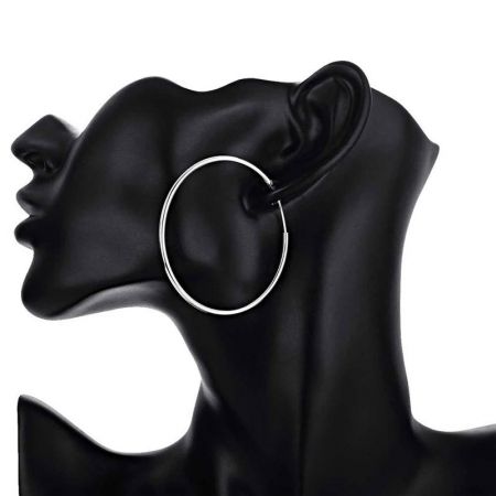 Side view of a large silver hoop earring on a black mannequin display.