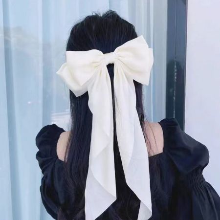 Um grande prendedor de cabelo em forma de laço de cauda longa branco estilizado em cabelo escuro.