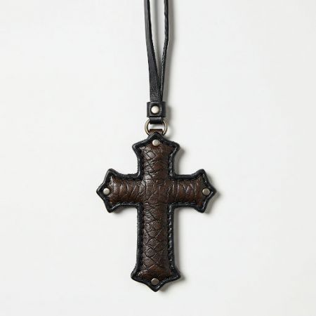 Ciondolo in pelle dettagliato a forma di croce con rivetti in argento, che mostra la personalizzazione degli accessori religiosi.