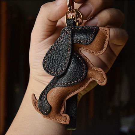 Gros plan du porte-clés en cuir de Basset Hound en noir et marron avec un anneau en métal doré.