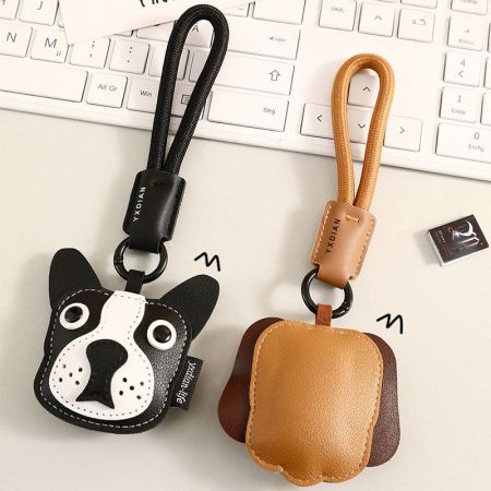 Le porte-clés Boston Terrier montré à côté d'une petite pochette en cuir assortie.