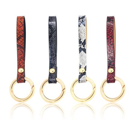 Llave de manija de bolsa de muñeca de cuero PU - Cuatro llaveros de manija de bolsa de muñeca de cuero PU en diferentes colores, cada uno con un llavero dorado pulido. Modelo JRK-003, un accesorio de moda versátil.