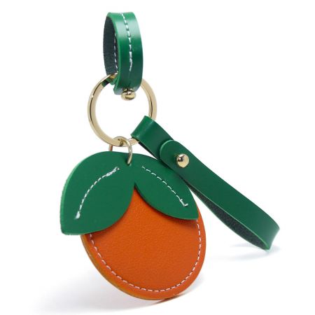 A green PU leather keychain in the shape of a tangerine with gold clasp, available for wholesale.