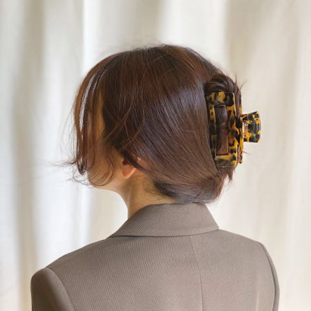 Una modelo mostrando un elegante moño bajo sostenido con un clip de garra de estampado de leopardo.