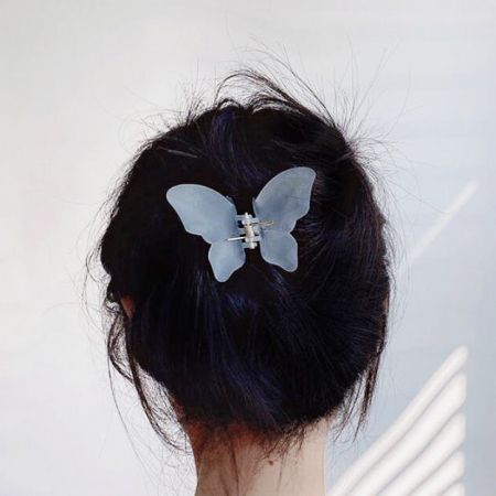 Una clip per capelli a forma di farfalla blu chiaro che tiene i capelli scuri di una donna in uno chignon.