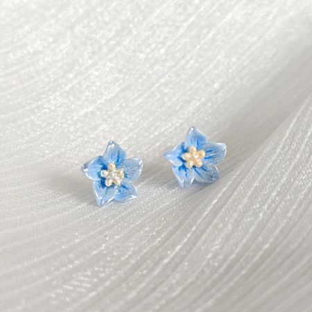 薄い青の樹脂製小花スタッドイヤリング（5ペア） - 白い中心を持つ薄い青の樹脂製小花スタッドイヤリングのペアが、クリーンな白い背景で表示されています。