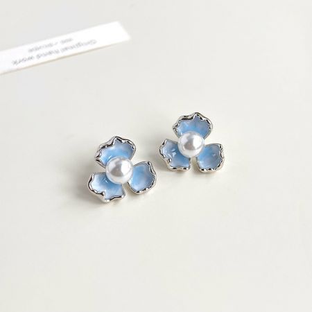 Angled shot of the gradient blue enamel flower earrings, showing their delicate shape.