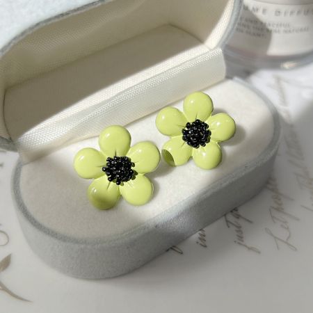 ハート型の箱に入った緑のデイジー花のイヤリングの上からのビュー。
