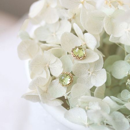 Lifestyle shot of 18K gold plated peridot earrings resting on delicate white flowers.