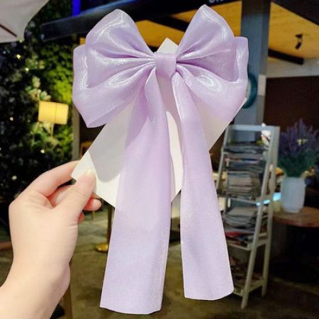 연한 보라색 두 겹 새틴 리본 헤어 클립의 클로즈업.