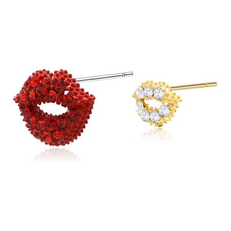 Vue rapprochée des boucles d'oreilles en forme de lèvres asymétriques rouges et dorées avec des détails en pierres précieuses.