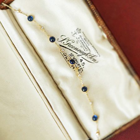 Elegantes vergoldetes Armband mit blauen Edelsteinen, präsentiert in einer luxuriösen Schmuckschatulle.