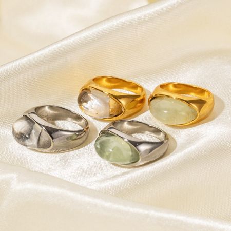 Anelli in Acciaio Inossidabile con Gemme Cabochon in Resina Trasparente (Set di 5) - Un set di anelli spessi in acciaio inossidabile con gemme cabochon in resina trasparente e verde, mostrati sia in finiture dorate che argentate, elegantemente esposti su uno sfondo satinato.