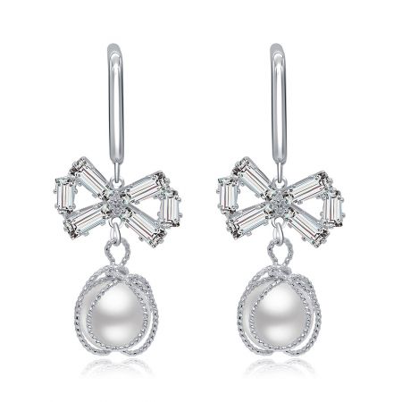 Pendientes de perla con gancho en forma de lazo. - Pendientes de perla con gancho en forma de lazo que presentan copas en forma de flor con piedras preciosas transparentes cortadas en baguette y elegantes perlas en forma de lágrima.