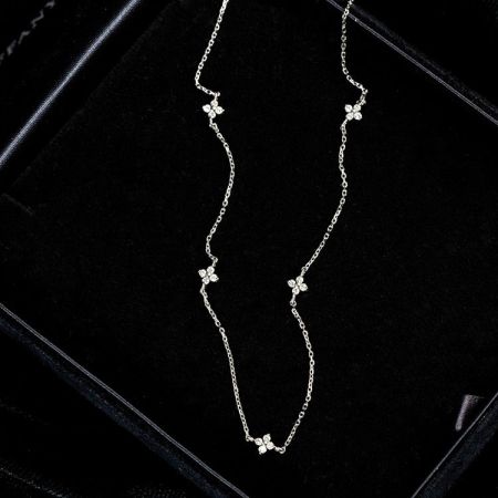 Un collar de plata lujoso con una cadena ondulada única y motivos similares a diamantes, exhibido en una caja de joyería.