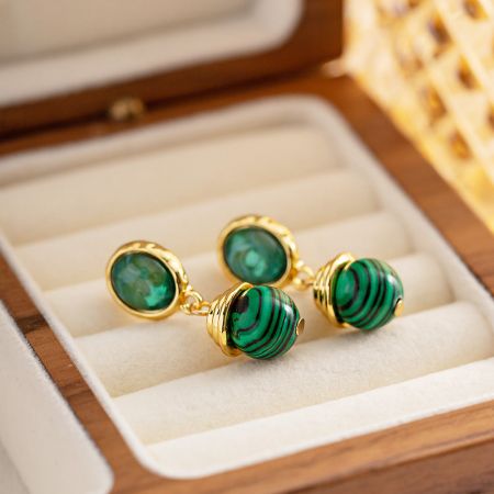 Close-up of a pair of drop earrings featuring striking green malachite stones set in polished gold-plated stainless steel.