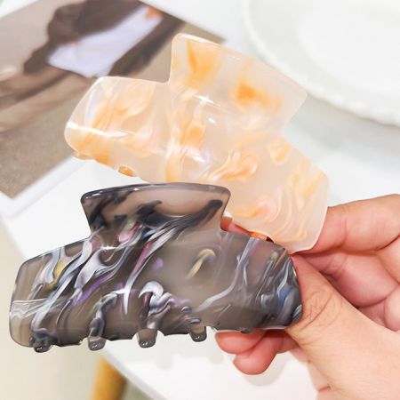 Two acetate hair clips in black and beige marbled designs.