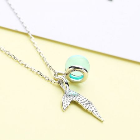 Collana con pendente a coda di sirena in argento elegante, accentuata da pietre trasparenti e una perla verde menta.