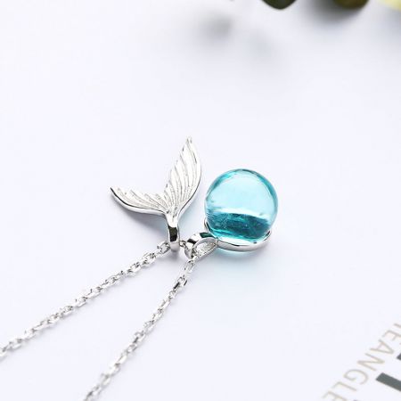 Collar con colgante de cola de ballena de piedra lunar de plata esterlina 925. - Un primer plano de un collar de plata esterlina 925 que presenta un delicado colgante de cola de ballena con una perla de luna azul claro brillante.