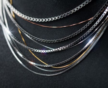 A collection of wholesale 925 sterling silver chains in various styles displayed on a black surface.