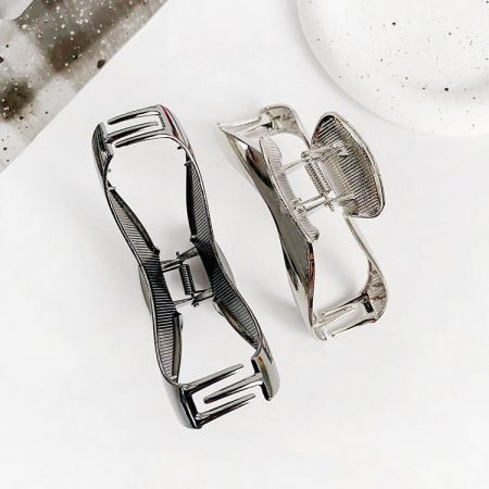 Two curve-shaped metal hair clips showcasing their strong spring mechanism and polished finish.