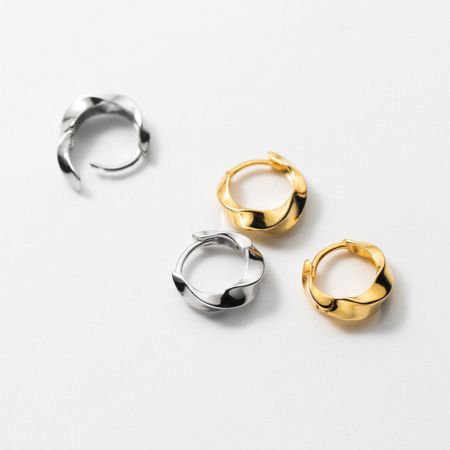 Le versioni in argento e oro degli orecchini a cerchio con spirale Mobius esposte insieme.