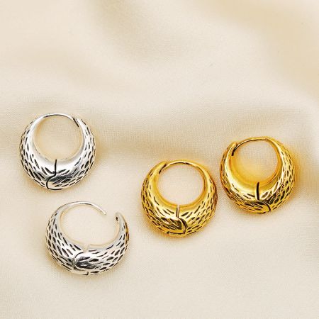 Detailed view of the textured, feather-like pattern on the silver and gold basket bag hoop earrings.