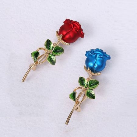 Close-up van de rode en blauwe emaille rozenbroches, met nadruk op het gedetailleerde vakmanschap en de vergulde stelen.