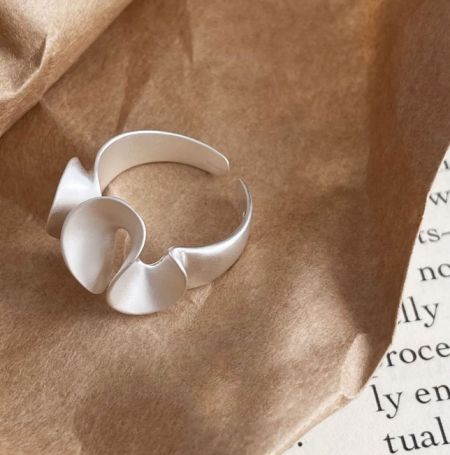 Scatto ravvicinato del anello opaco a foglia di loto irregolare in argento sterling 925, evidenziando la sua forma astratta e la finitura opaca.