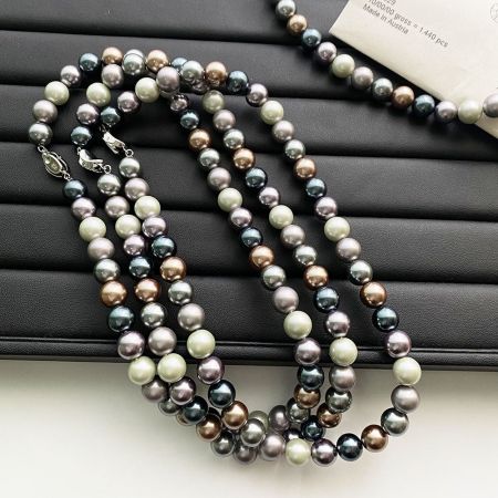 Multiple strands of Morandi-colored pearl necklaces arranged on a black display.