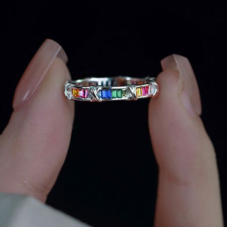 Toma de producto detallada de un solo anillo de cruz de plata esterlina con piedras de zirconia multicolores.