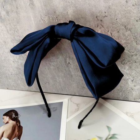 Un primer plano de una sofisticada diadema de seda azul marino con un gran lazo.