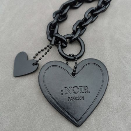 Charm en forme de cœur noir personnalisé avec le logo 'NOIR FASHION', parfait pour les articles promotionnels.
