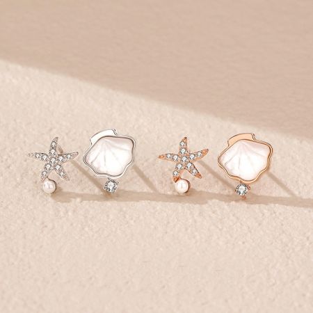 Orecchini a perno asimmetrici in argento sterling 925 a forma di conchiglia e stella marina con perla (set di 5 paia) - Un set di orecchini a perno a tema oceanico in argento sterling 925, che mostrano design di stelle marine e conchiglie in finiture sia in argento che in oro rosa su uno sfondo bianco.