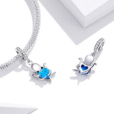 Een sieradenset met de zilveren octopusbedel met blauwe opaal aan een ketting en oorbel.