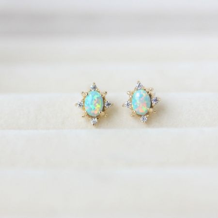 925 Zilver Gouden Ovale Vierpoots Opaal Studoorbellen - Een paar 925 sterling zilveren goudvergulde ovale studoorbellen met vierpoots opaalstenen en diamantaccenten, getoond op een schone witte achtergrond.