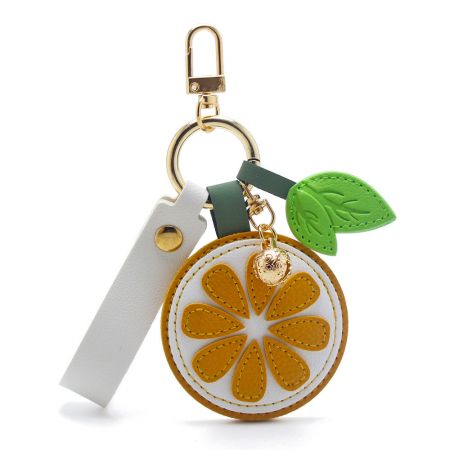 A white PU leather wristlet with a vibrant orange slice charm and gold hardware.