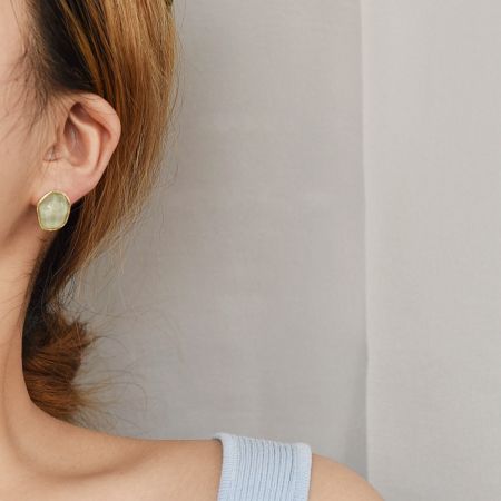 Close-up of a model wearing the pale green resin stud earring.